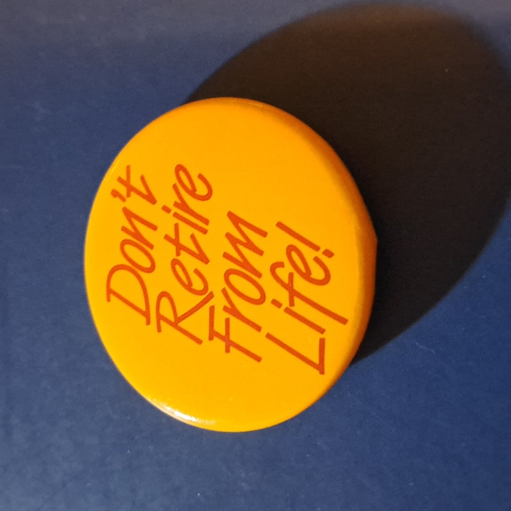 Don't Retire From Life! Pin button orange yellow with red writing